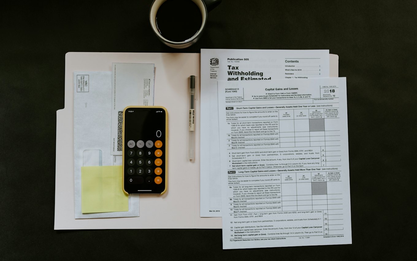 Tax forms, a pen and a smartphone calculator on a desk