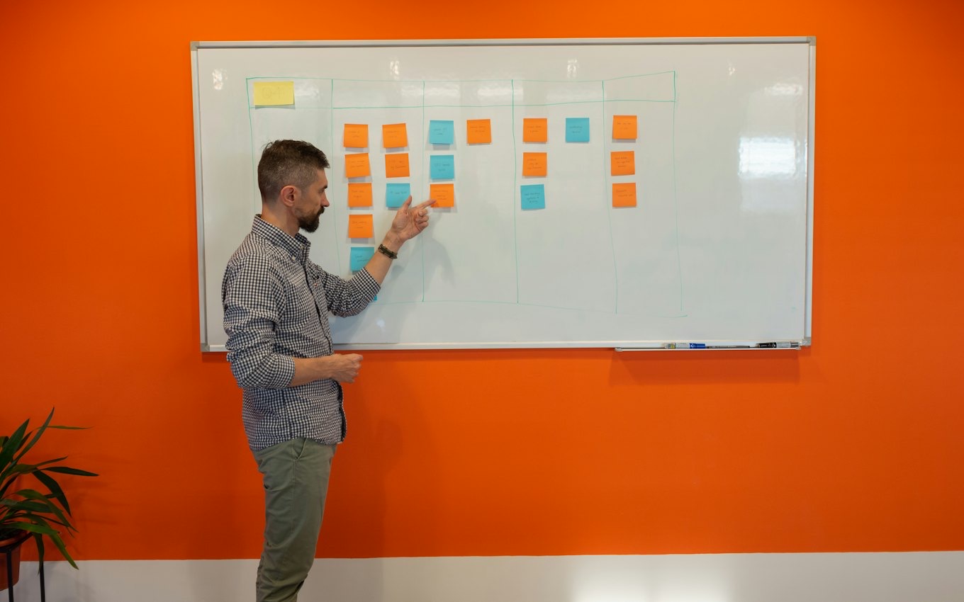 A man presenting at a whiteboard covered in sticky notes