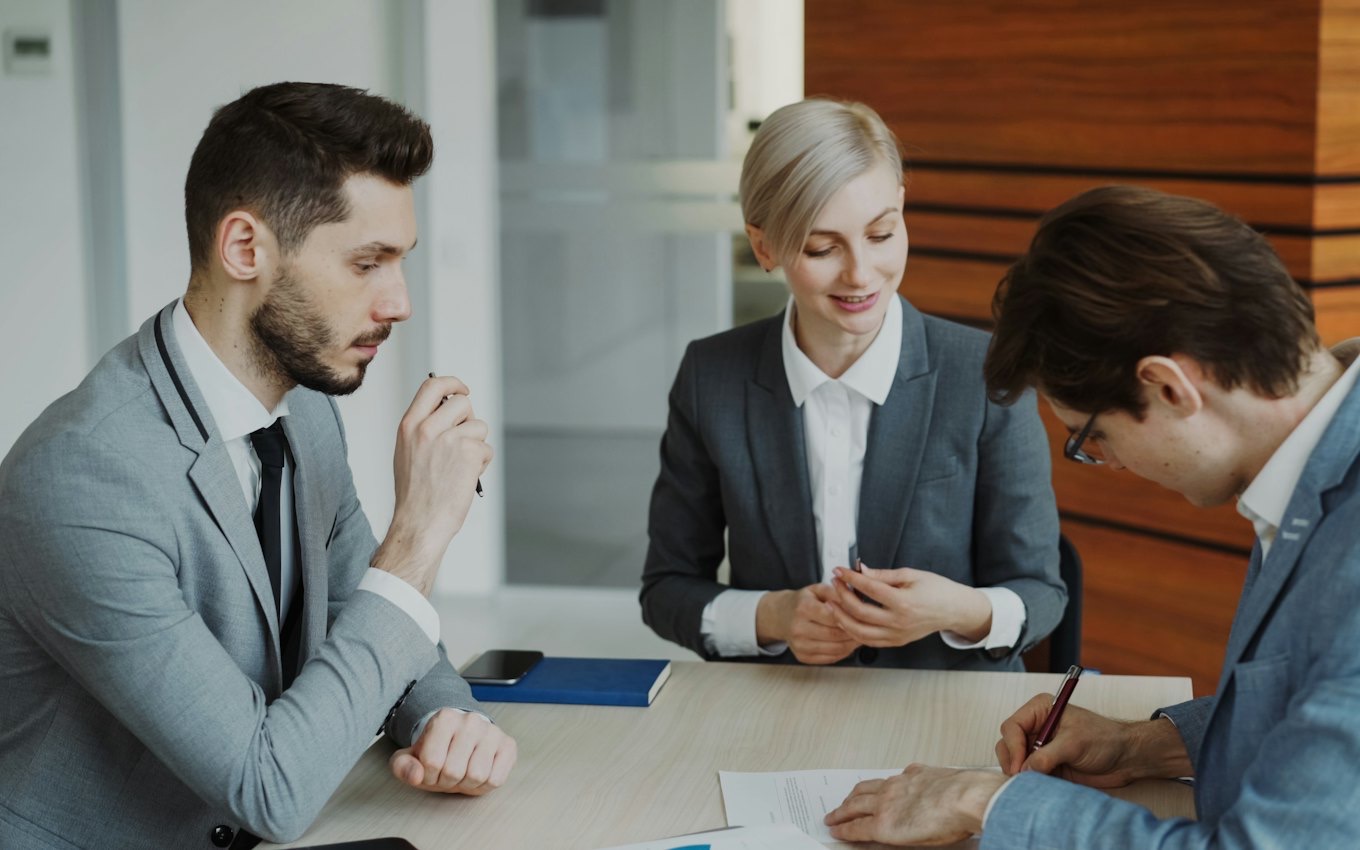 Three colleagues reviewing documents at a conference table