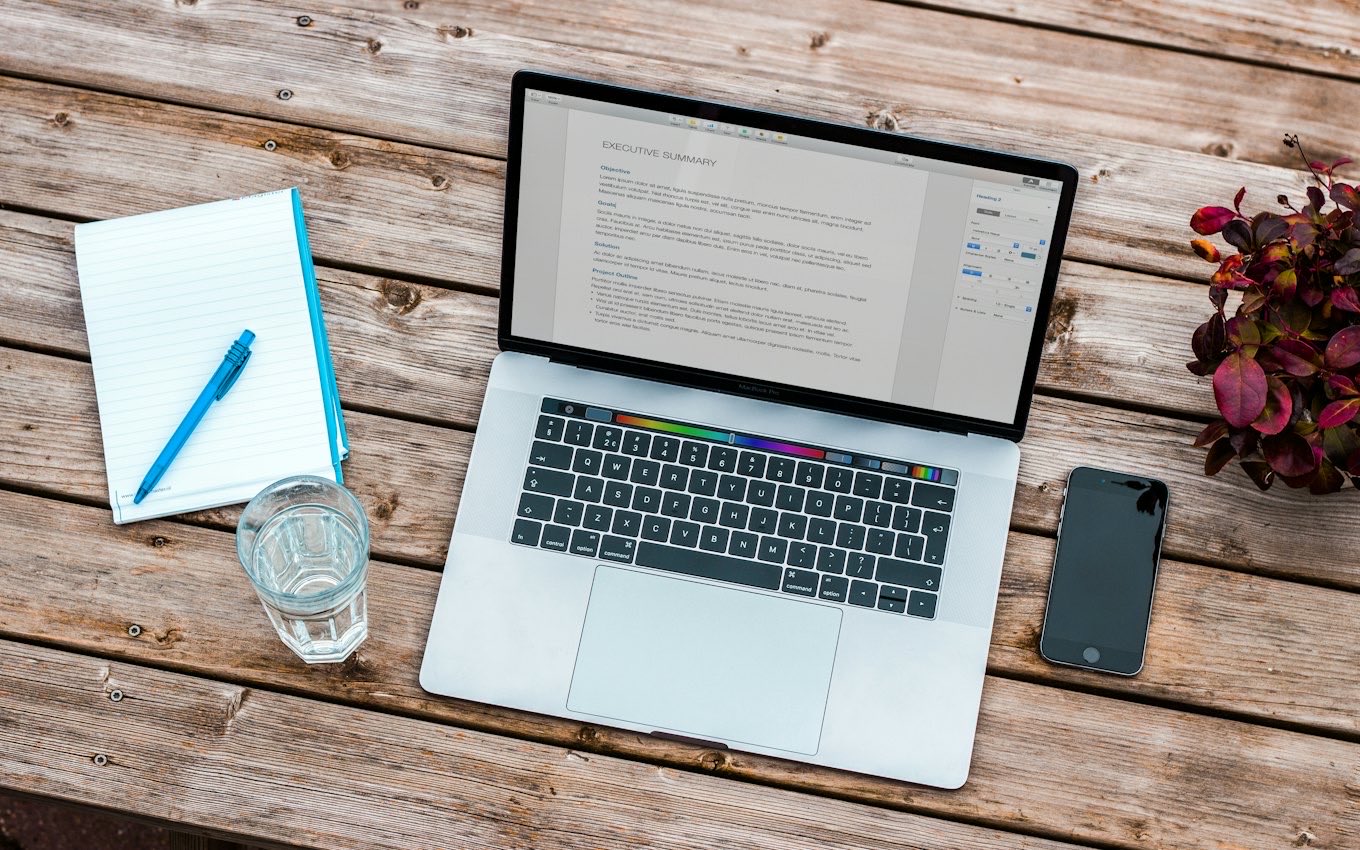 A laptop, phone and glass on a wooden desk