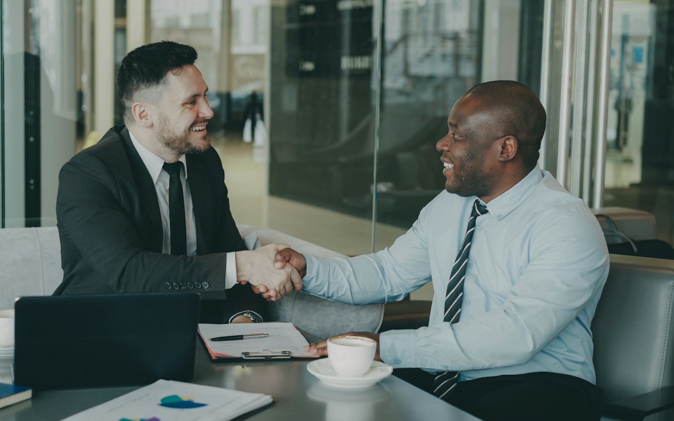 Two business people shaking hands across a desk