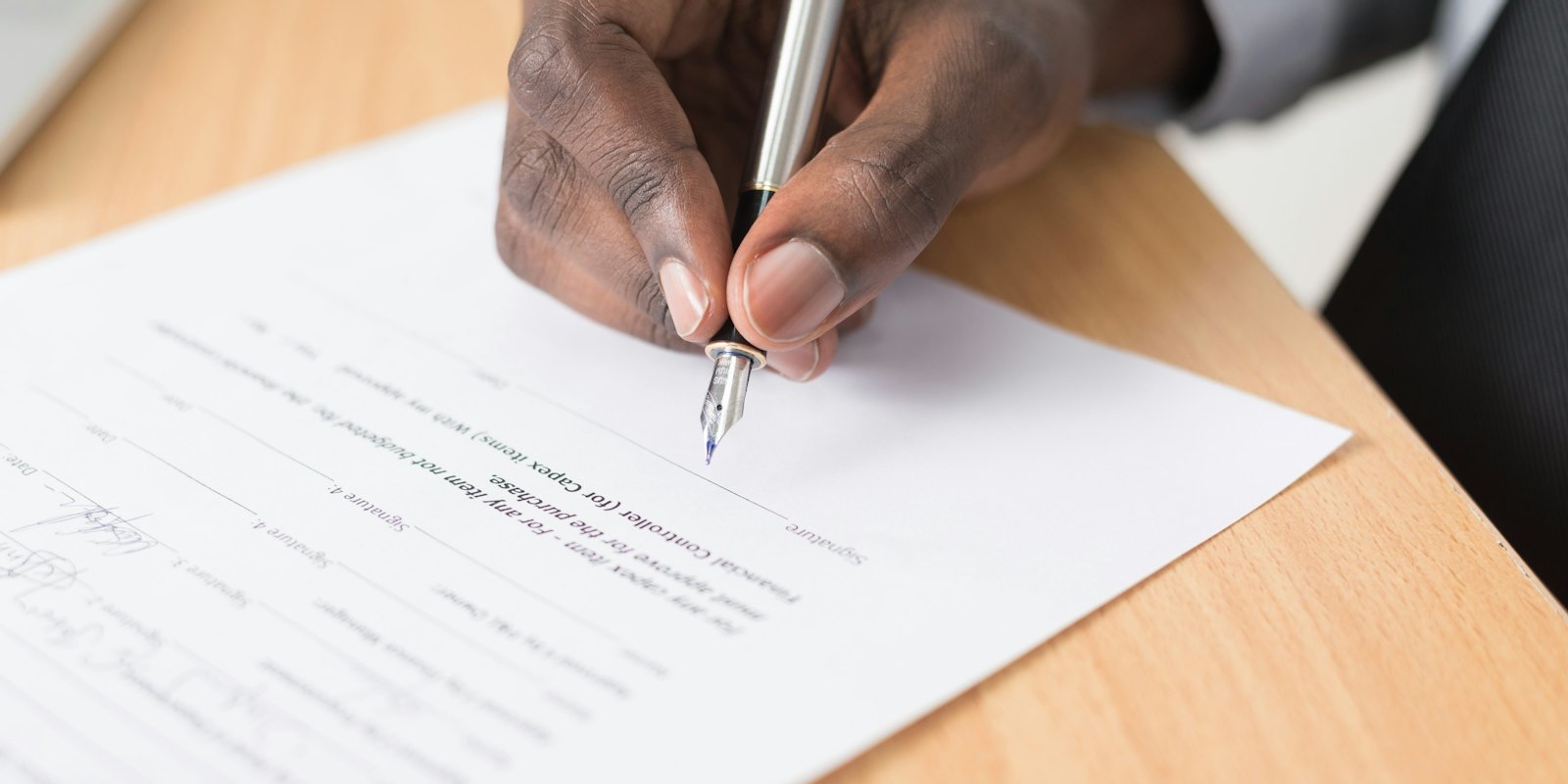 A person signing a printed contract with a pen