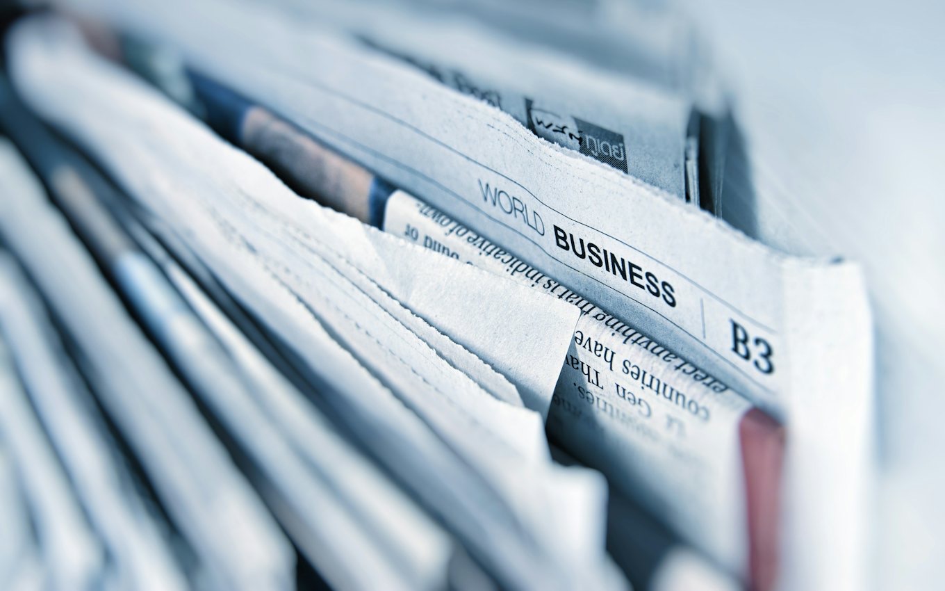 A close-up of stacked business newspapers