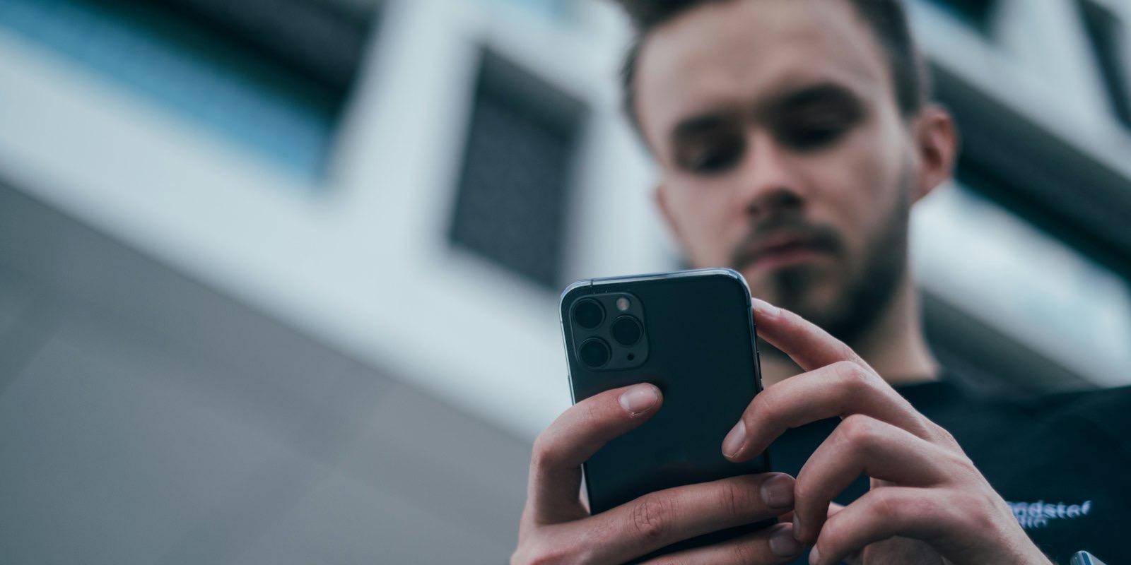 A man in a dark sweater looking at his smartphone