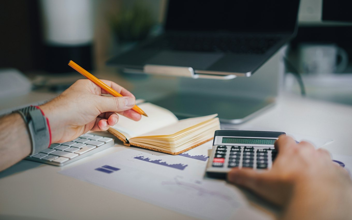 A person at a desk with a calculator and a notebook