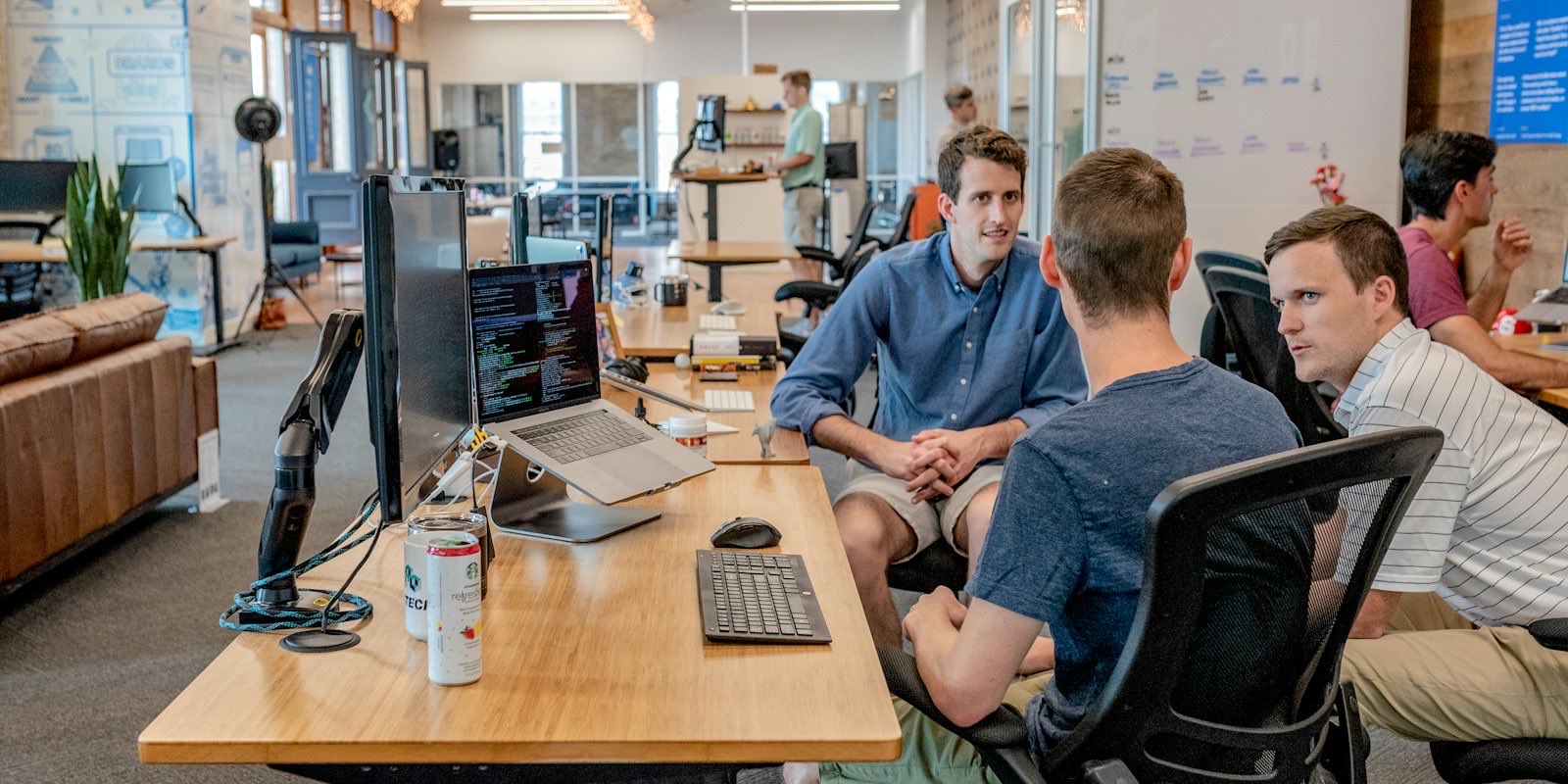A team at shared desks working across laptops and monitors in an open office