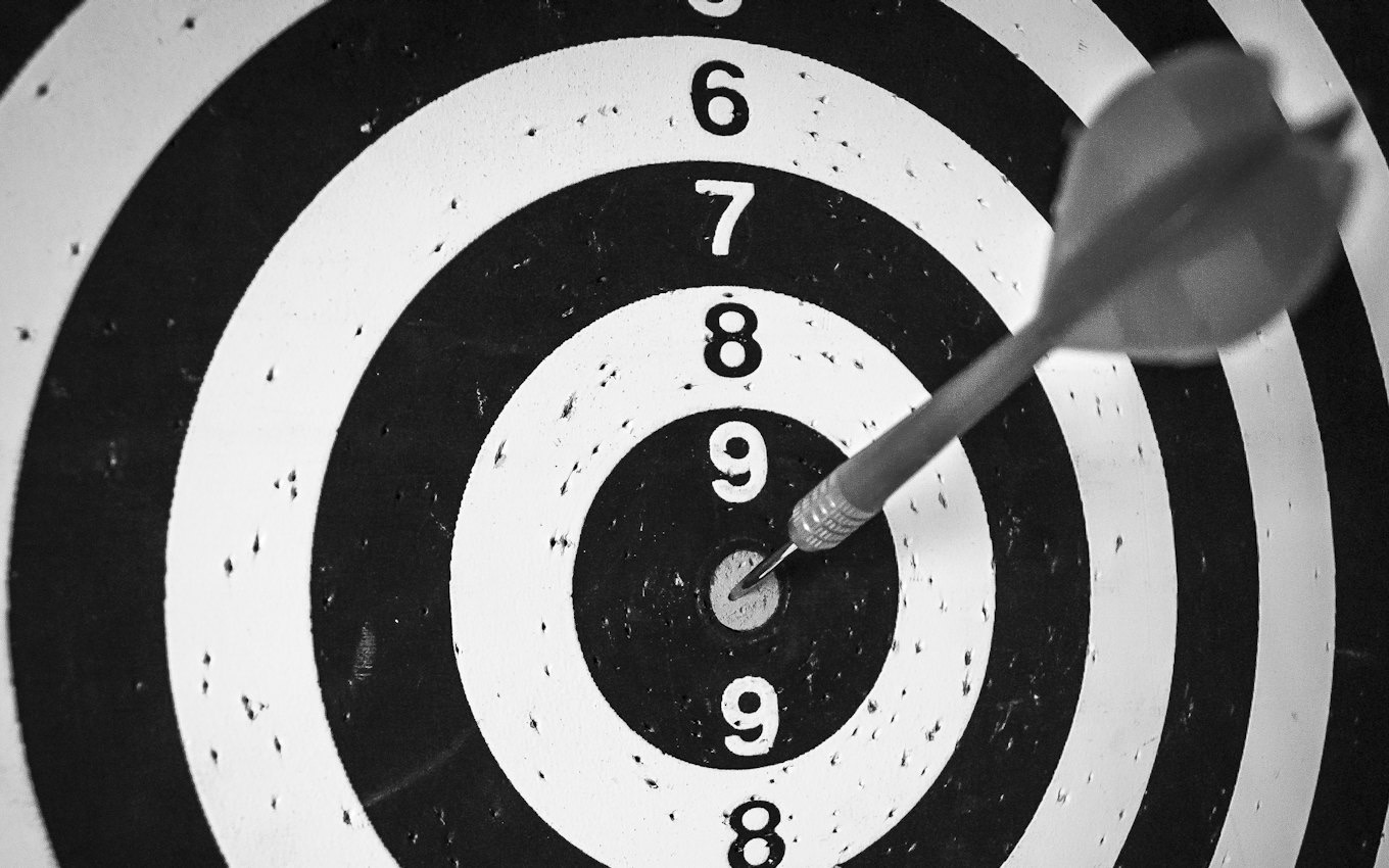 A single dart in the centre of a black and white dartboard