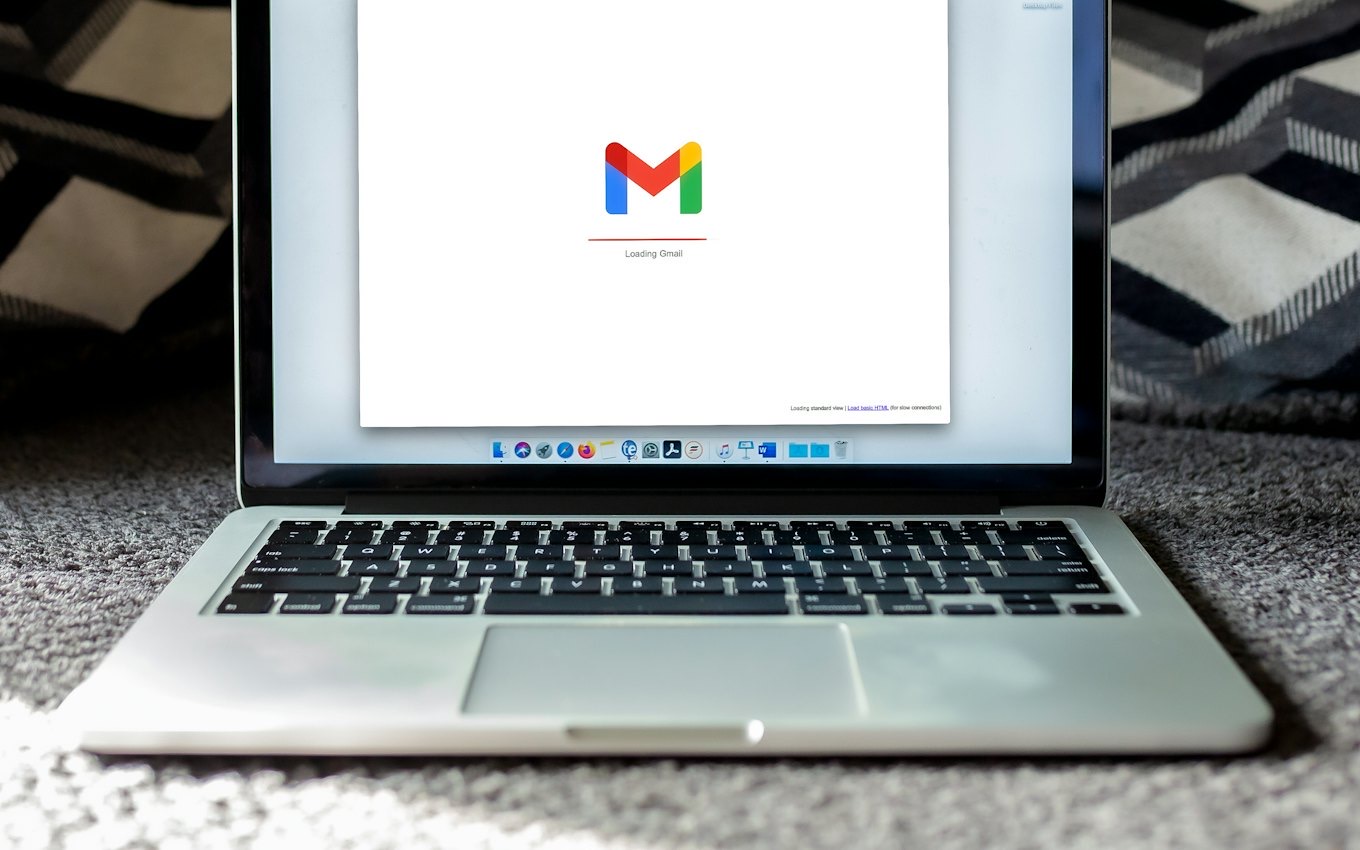 A laptop showing an email inbox on a dark surface