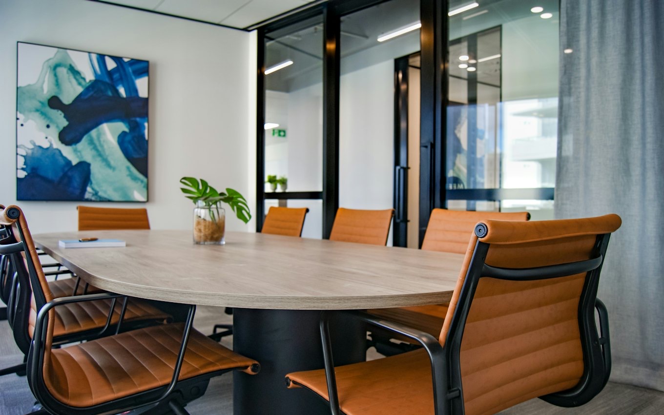 An empty conference room with a round table and leather chairs